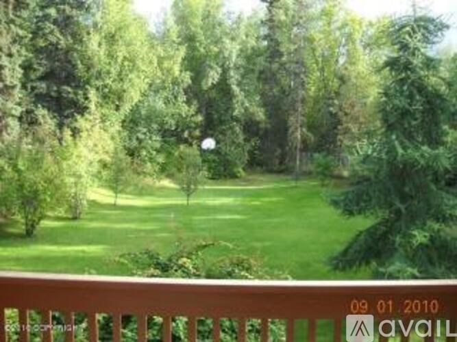 A green lawn with trees and a white ball in the distance.