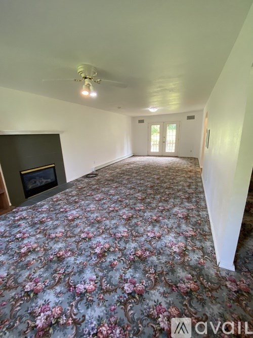 A room with a floral carpet and a fireplace.