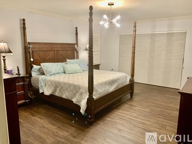 A bedroom with a four poster bed and a wooden floor.