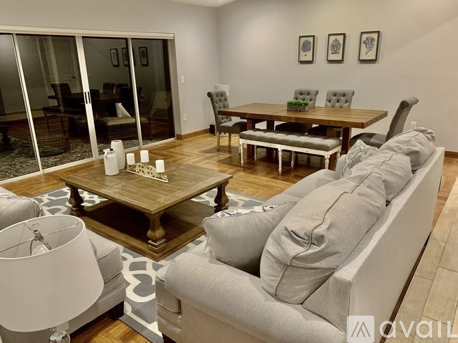 A modern living room with a grey sofa, wooden coffee table, and glass doors leading to a balcony.