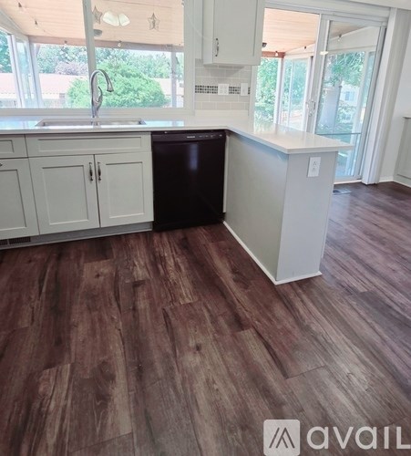A kitchen with white cabinets and a black dishwasher.