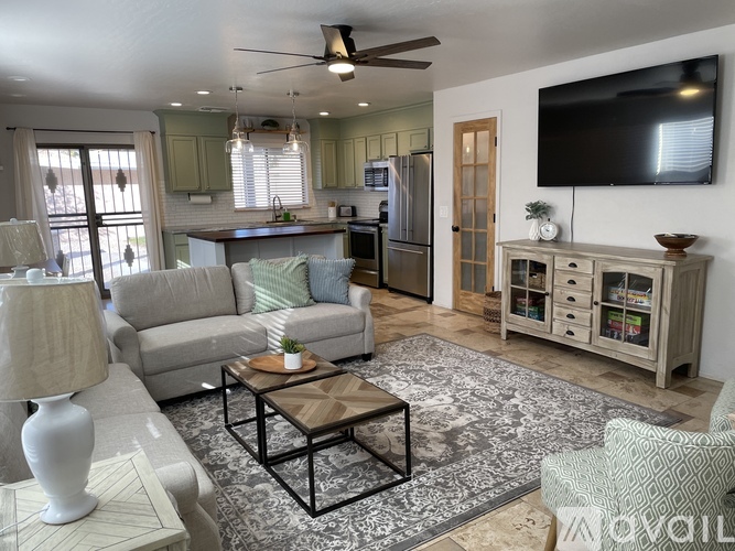 A living room with a grey couch, a coffee table, and a television on the wall.