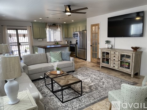 A living room with a grey couch, a coffee table, and a television on the wall.