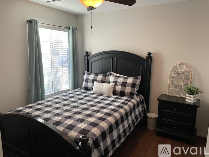 A bedroom with a bed, nightstand, and window.