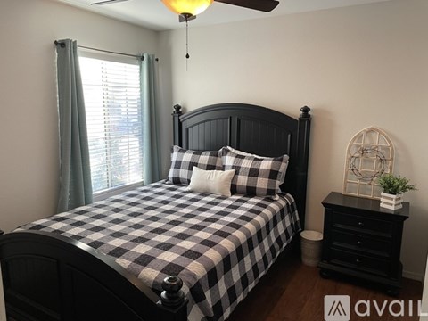A bedroom with a bed, nightstand, and window.