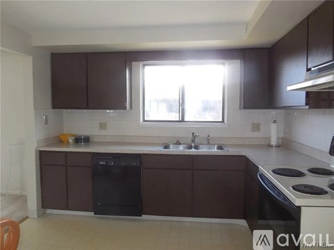 A kitchen with brown cabinets and a black dishwasher.