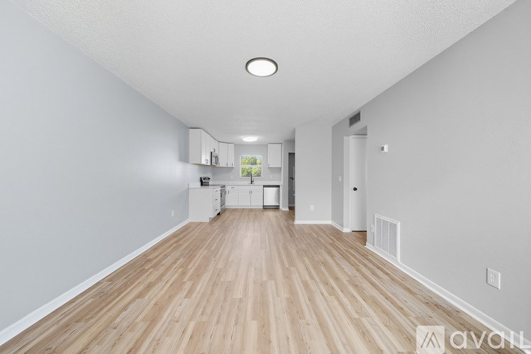 A long, empty hallway with wooden floors and white walls.
