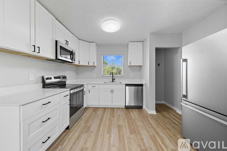A kitchen with white cabinets and a wooden floor.