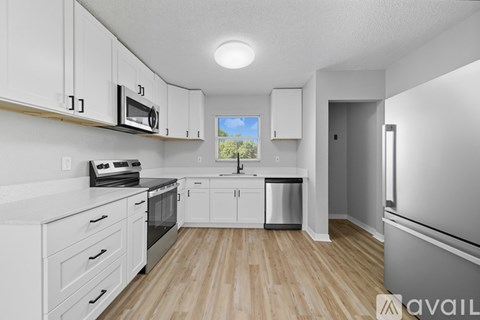 A kitchen with white cabinets and a wooden floor.