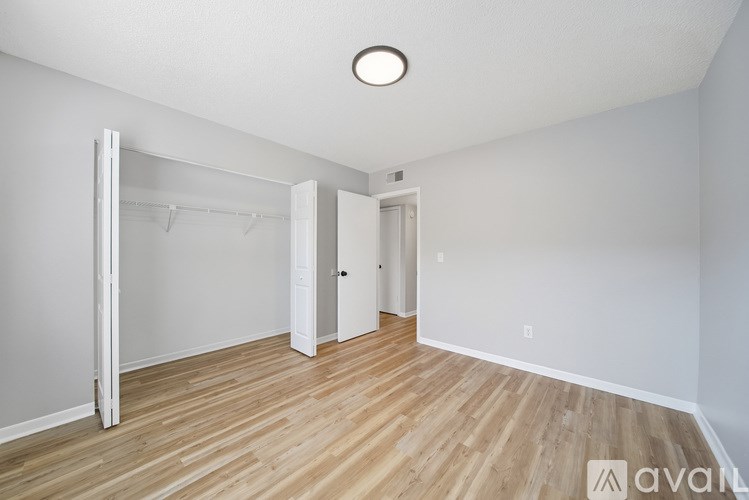 A room with a wooden floor and white walls, with a door and a wardrobe.