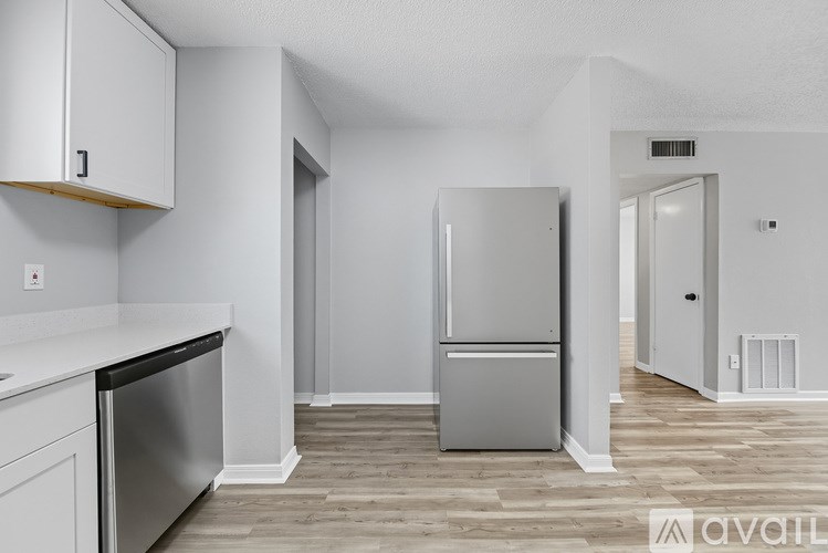 A kitchen with a refrigerator, dishwasher, and cabinets.