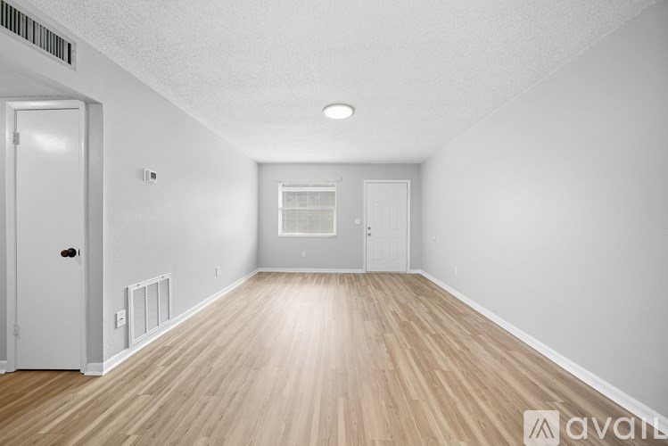 A spacious room with wooden flooring and white walls.