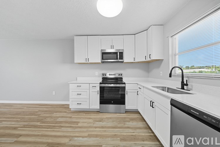 A kitchen with white cabinets and a wooden floor.