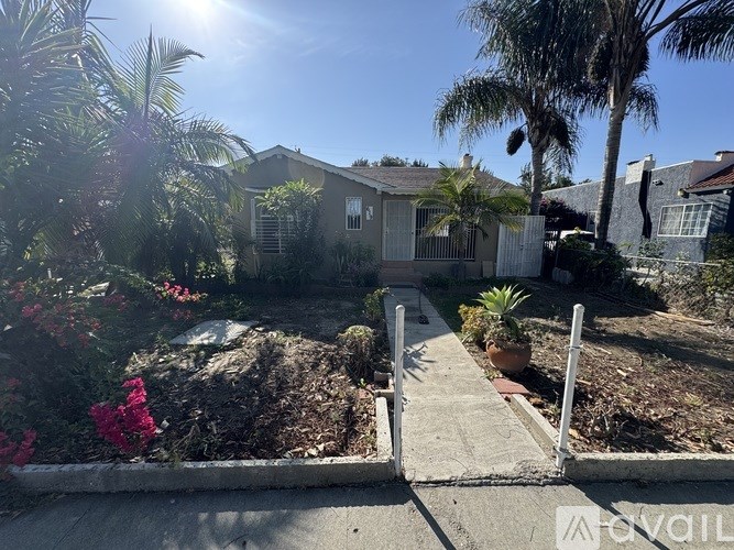 A sunny day in a residential area with a house and a garden.