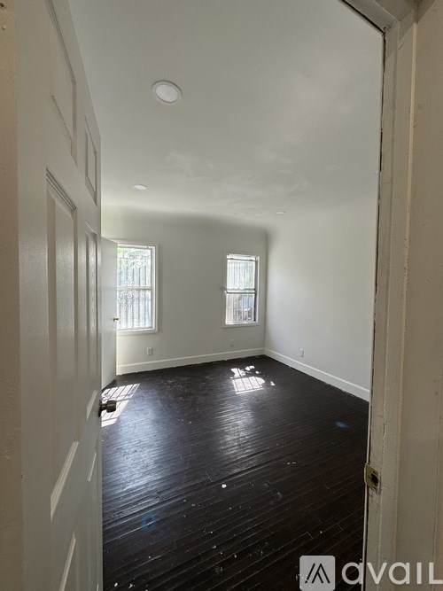 A room with wooden floors and two windows.