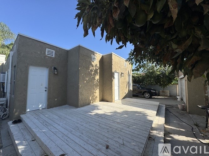 A house with a wooden deck and a car parked in the driveway.