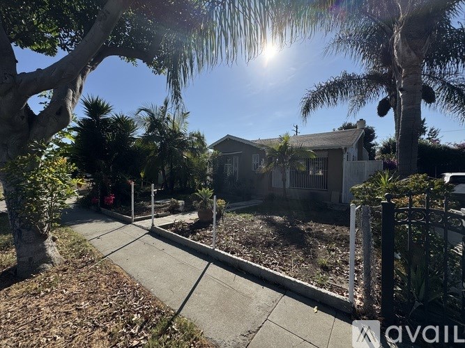 A house is for sale in a sunny, tree-lined neighborhood.