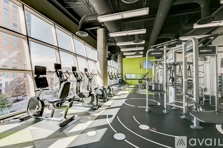 A gym with a row of treadmills and elliptical machines.