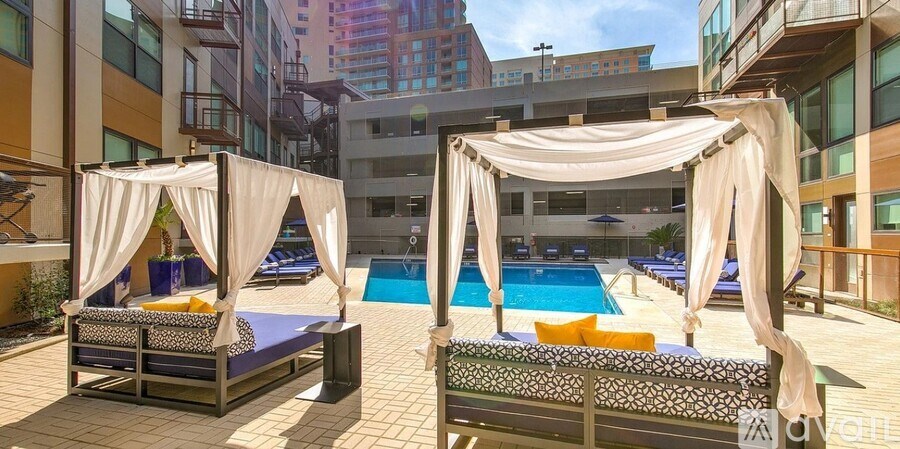 A poolside area with two canopied beds and a pool.