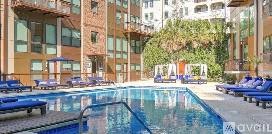 A large swimming pool surrounded by lounge chairs and umbrellas in a modern building.