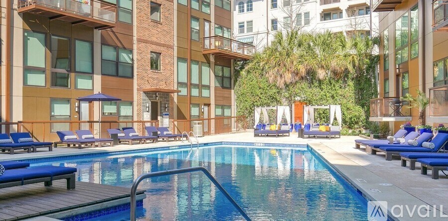 A large swimming pool surrounded by lounge chairs and umbrellas in a modern building.
