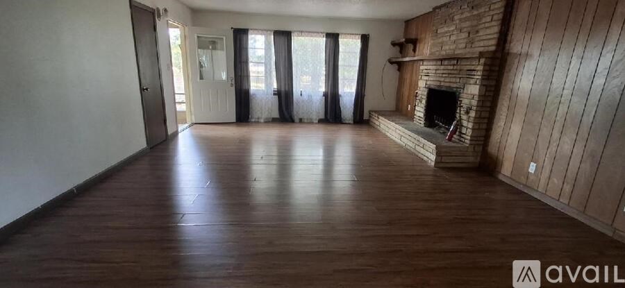A spacious room with wooden floors and a fireplace.