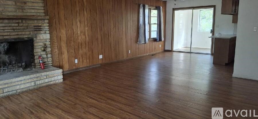 A living room with wood floors and a stone fireplace.