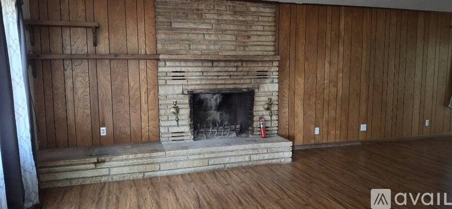 A room with a stone fireplace and wooden walls.
