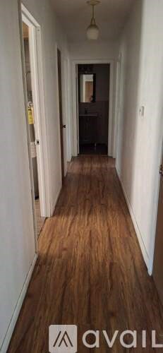 A long hallway with wood floors and white walls.