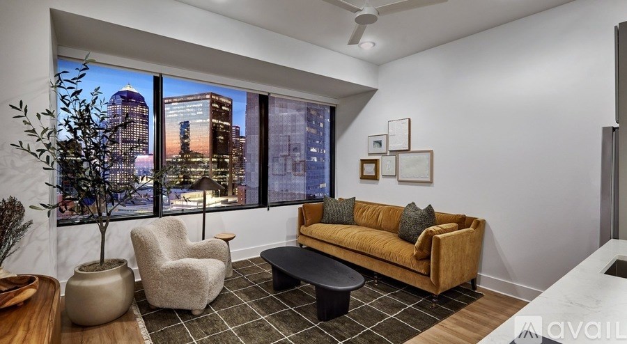 A living room with a couch, chair, and a potted plant.