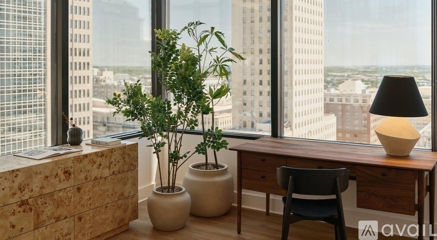 A room with a desk, chair, and potted plants.