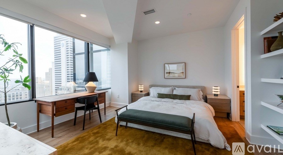 A bedroom with a large bed and a desk with a chair.