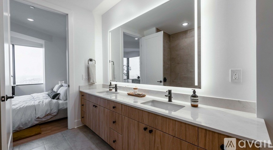 A bathroom with a large mirror, a sink, and a bed.
