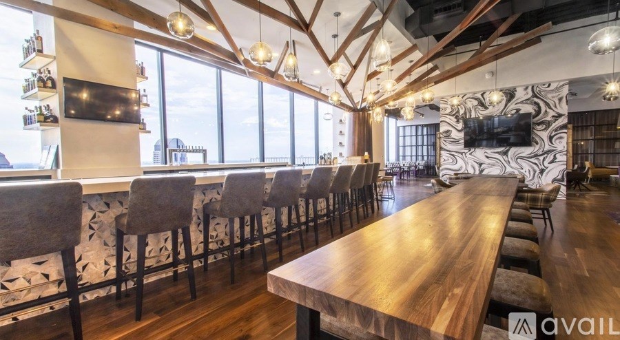 A long wooden table is surrounded by chairs in a room with a large window.