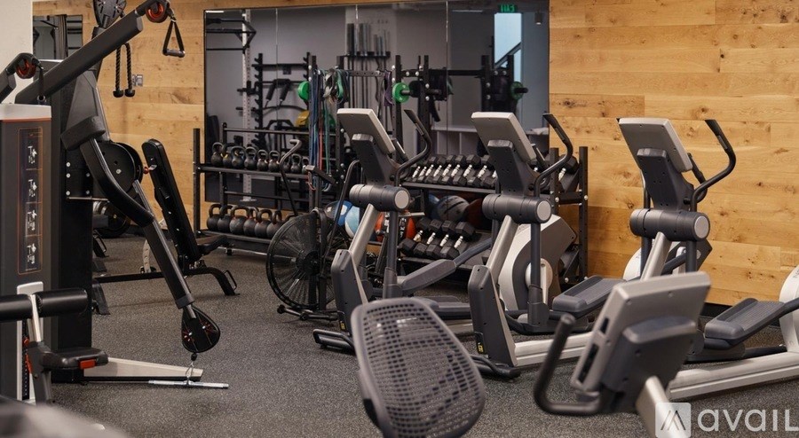 A gym with a variety of exercise equipment including treadmills, stationary bikes, and weight machines.