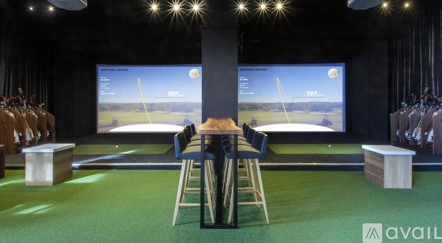 A room with a green carpet and a large screen displaying a golf game.