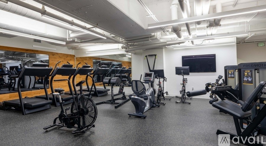 A gym with a variety of exercise equipment including treadmills, stationary bikes, and elliptical machines.