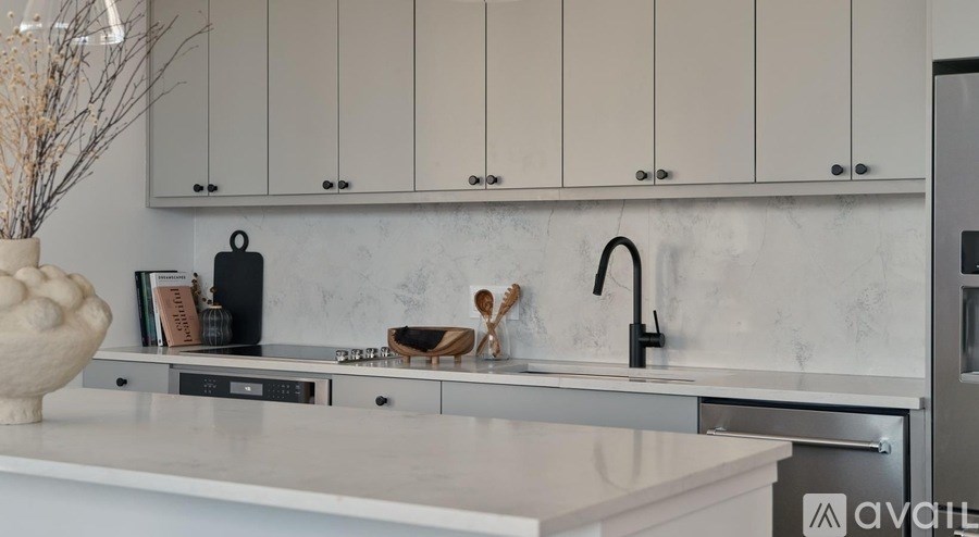 A kitchen with white cabinets and a marble backsplash.