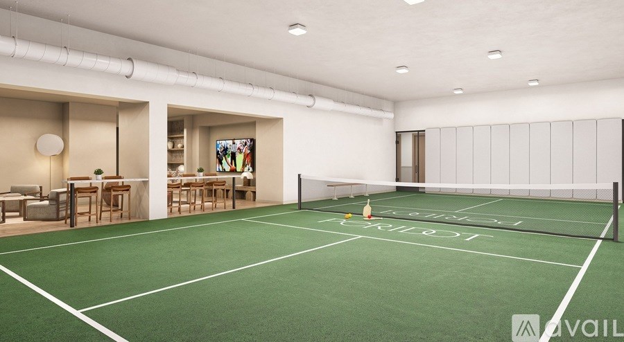 A tennis court is located in a spacious room with a white ceiling and walls.