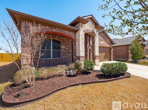 A house with a brown roof and a brick facade with a garden in front.