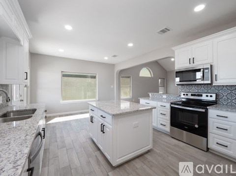 A modern kitchen with white cabinets and stainless steel appliances.
