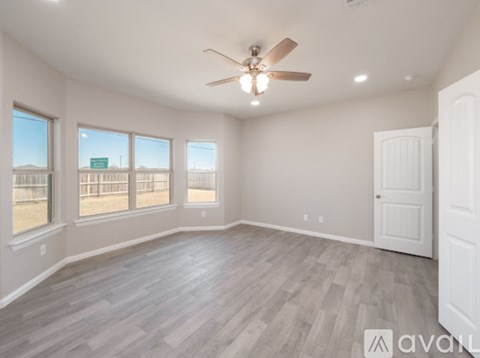 A spacious room with a ceiling fan and large windows.