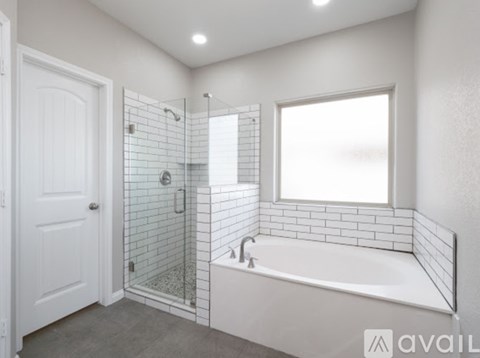 A white bathroom with a tub, shower, and a window.