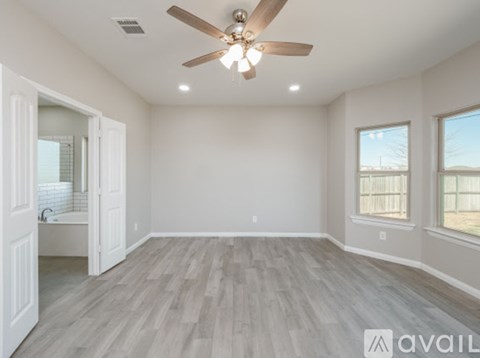 A spacious room with a ceiling fan and lighting fixture, and a window with a view of a fence and sky.