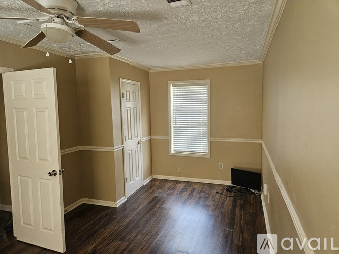 A room with a ceiling fan and wooden floors.