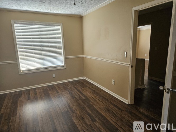 A room with wooden floors and a window with blinds.