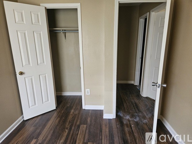 A room with a white door and a wooden floor.