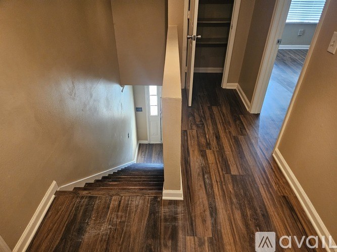 A hallway with wood flooring and a staircase.