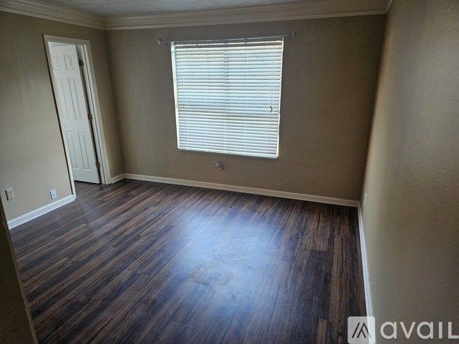 A room with wooden flooring and a window with blinds.
