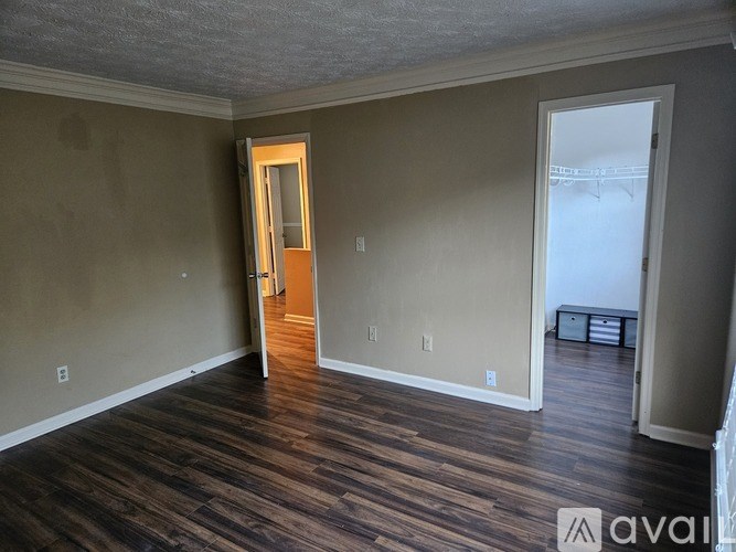A room with wooden flooring and a window with blinds.